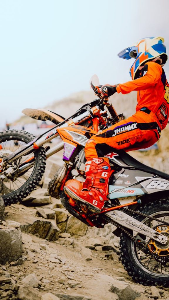 Motocross rider in vibrant gear navigating rocky terrain in Indonesia, showcasing skill and determination.